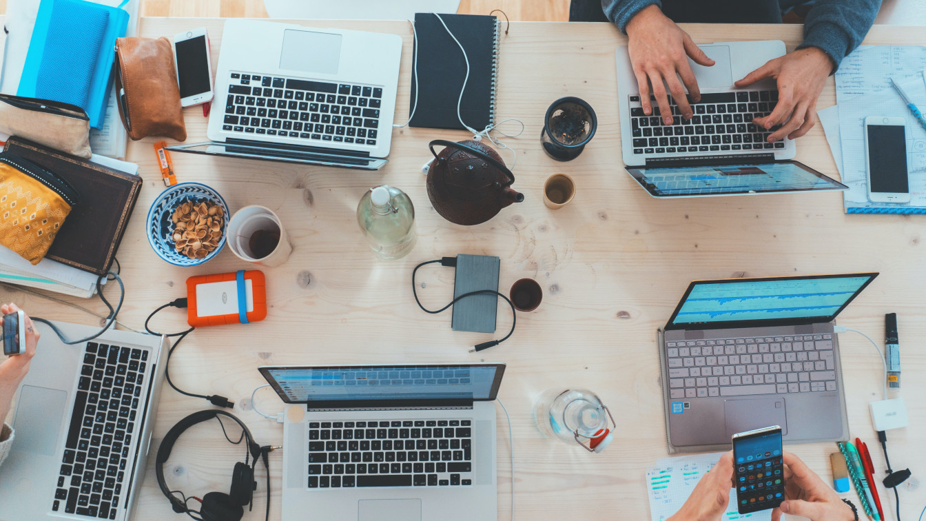 A desk with various computers, phones and related technology